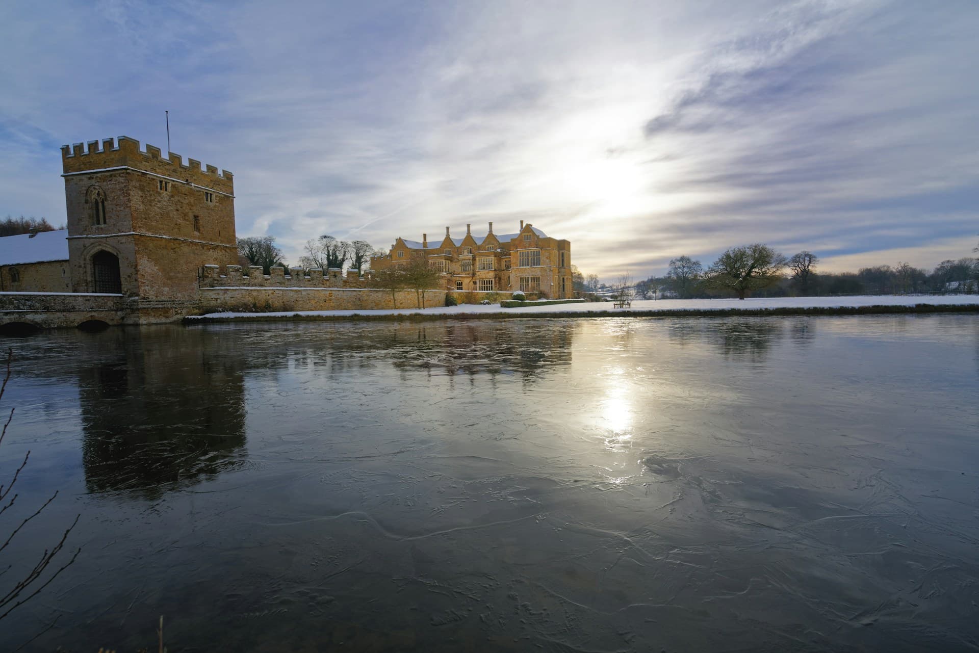 Broughton Castle near Banbury beside its frozen moat on a snowy winter day