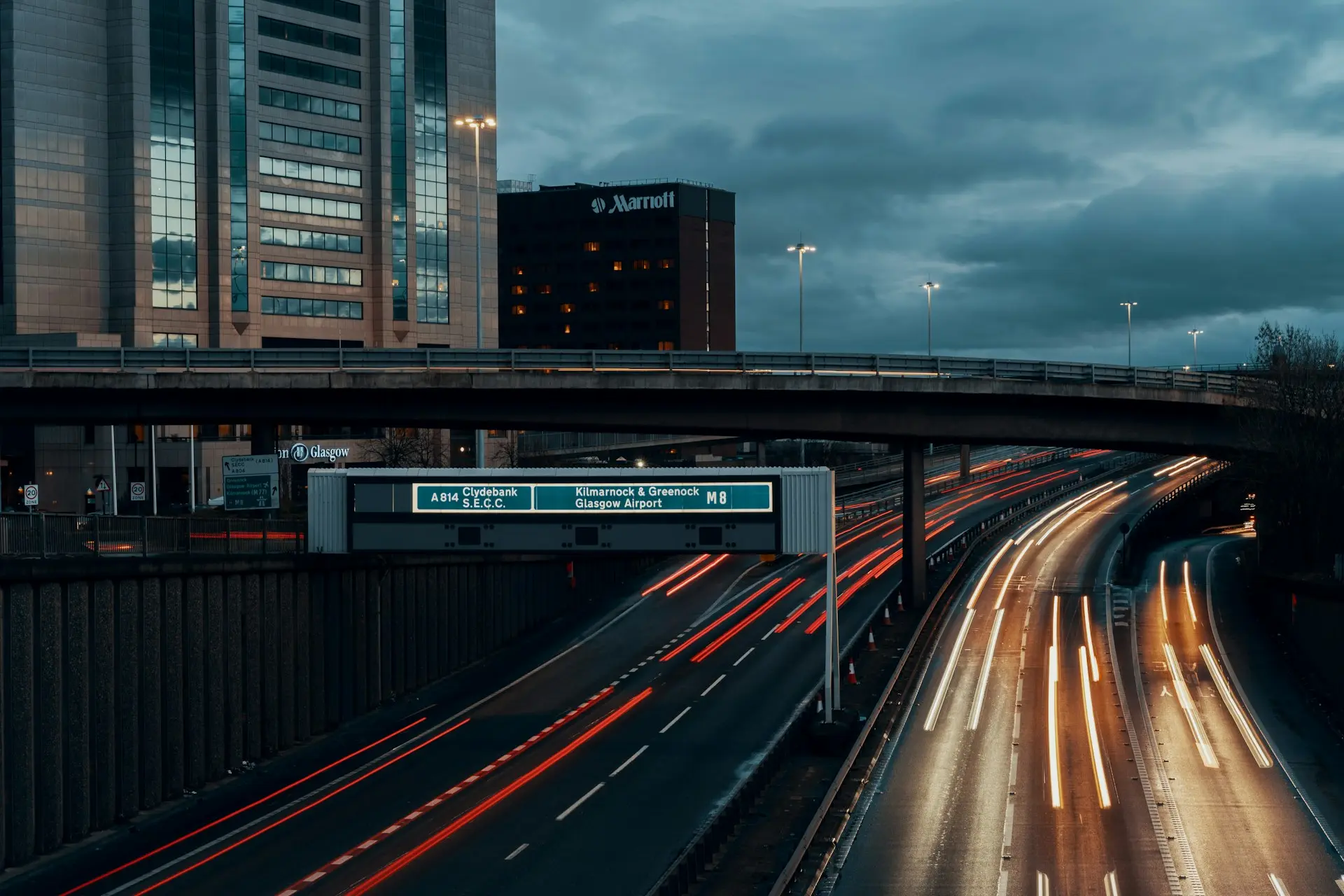 Motorway traffic light trails under a flyover at dusk